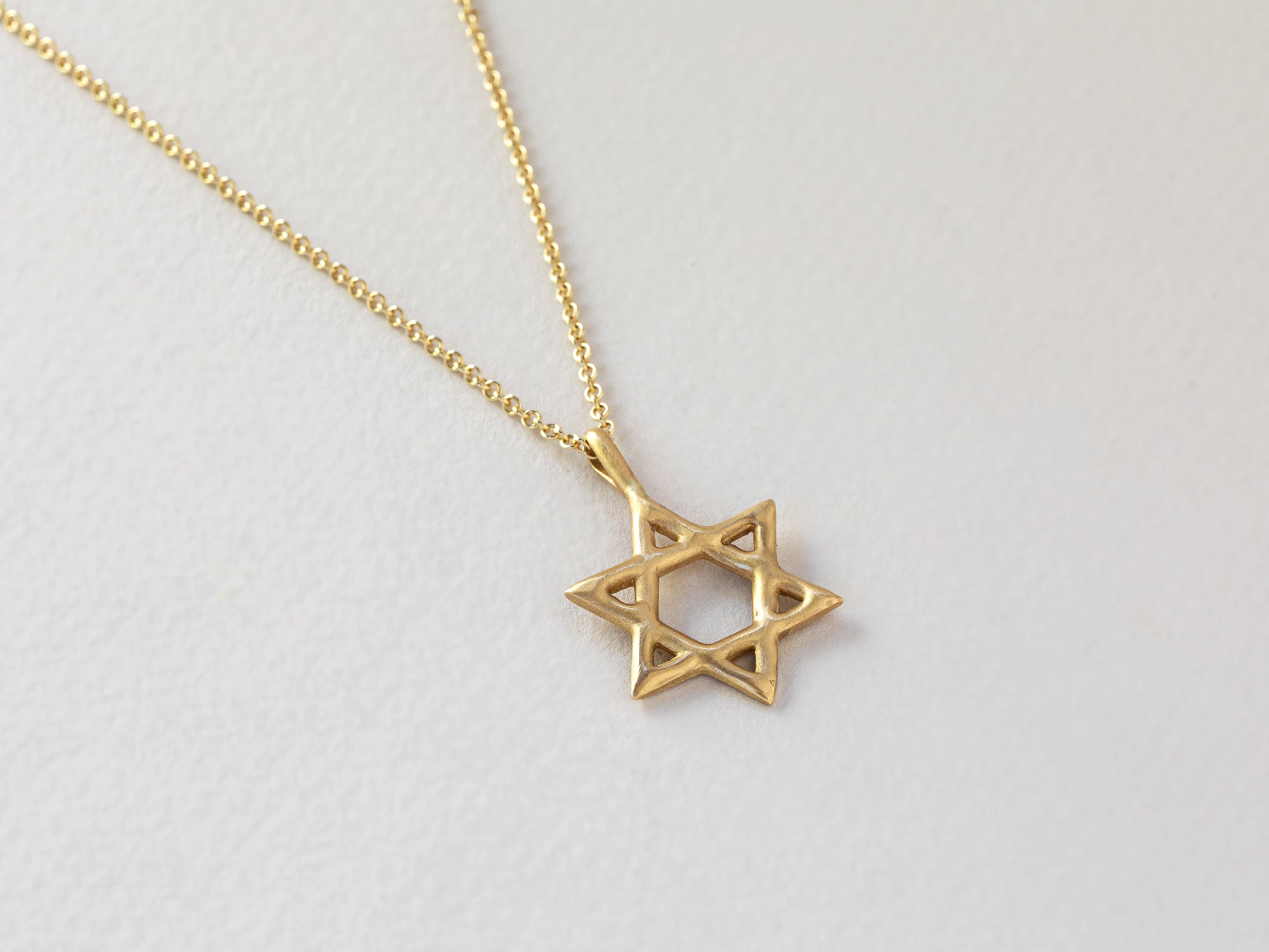 תליון מגן דוד זהב מיוחד. עשוי זהב 14 קראט, מפוסל בעבודת יד במראה גולמי