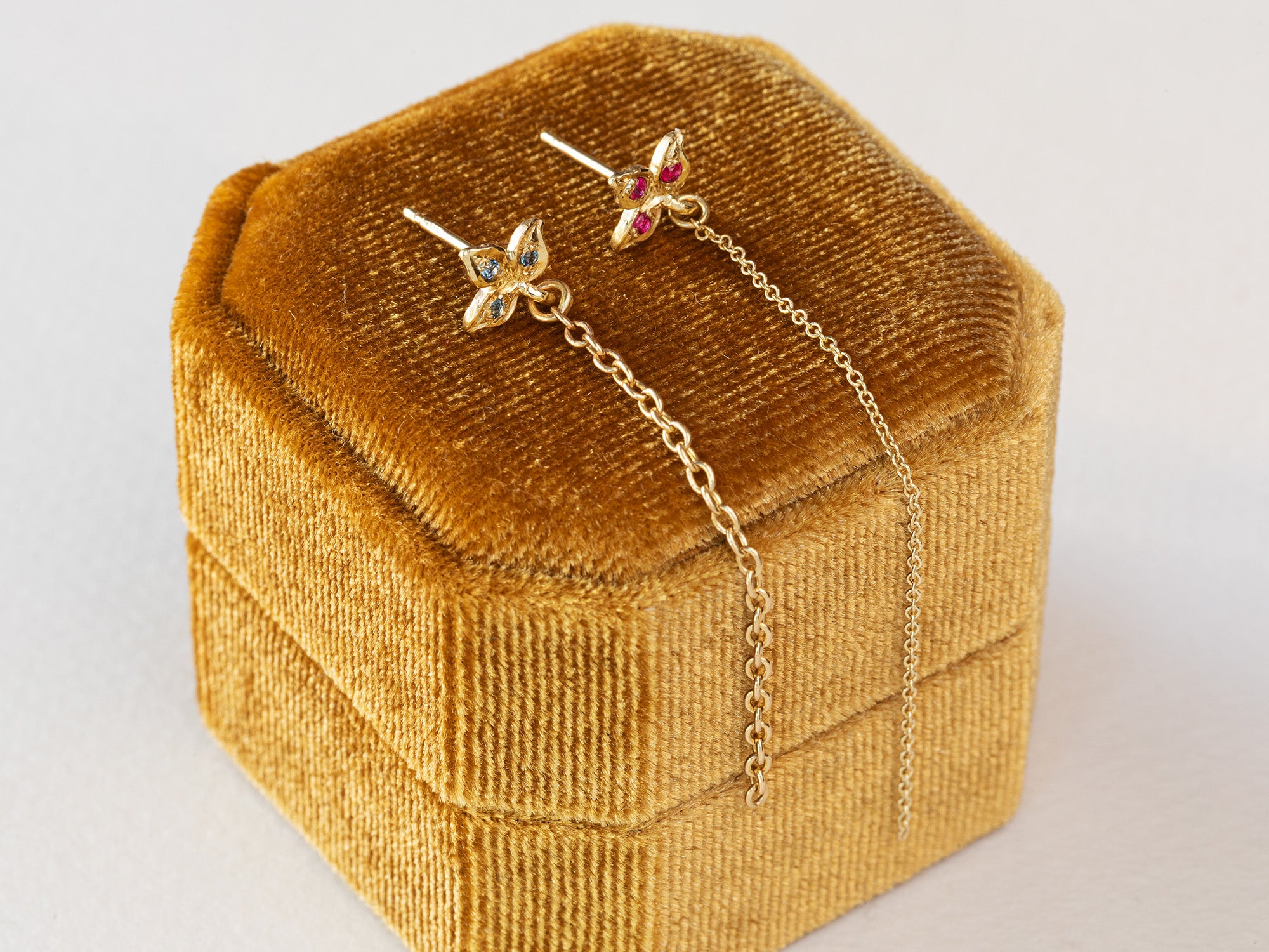 עגיל עלה תלתן מעוצב מזהב 14 קראט משובץ אבני בלו טופז עם שרשרת זהב משתלשלת ממנו.