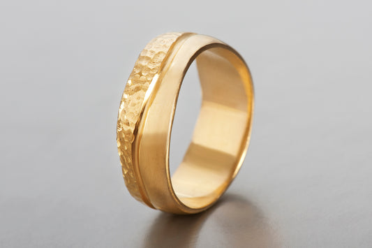 היא טבעת יוניסקס רחבה. טבעת זהב עשויה בעבודת יד בסטודיו שלנו, הטבעת מעוגלת קלות ובמרכזה עובר קו גלי שחרוט בתוך החומר. חצי מהטבעת בגימור מבריק וחציה השני מובלט על ידי טקסטורה מחוספסת.