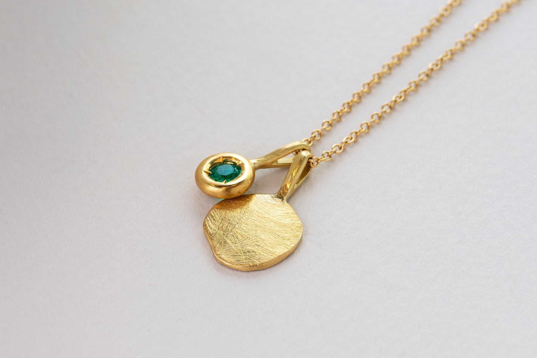 שרשרת חוליות זהב צהוב 18 קראט עם תליון יגול אמורפי מזהב ותליון כוס זהב משובצת אמרלד ירוק.