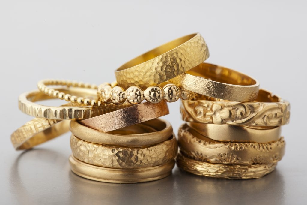 מערום טבעות זהב מונחות אחת על השניה. טבעו הב מיוחדות עשויות בעבודת יד ומעוצבות בסטודיו הידרה.