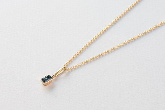 שרשרת חוליות זהב עדינות ותליון זהב עם וו ארוך בצורת מלבן משובץ טורמלין כחול.