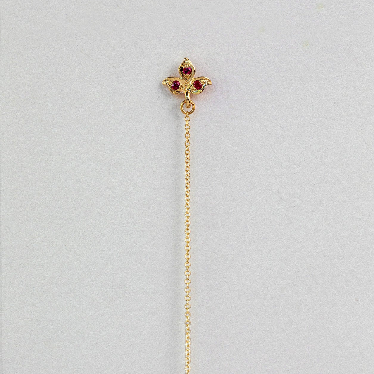 עגיל זהב  עלה תלתן צמוד אוזן  שממנו יוצאת שרשרת חוליות זהב. משוב אבני רובי 
