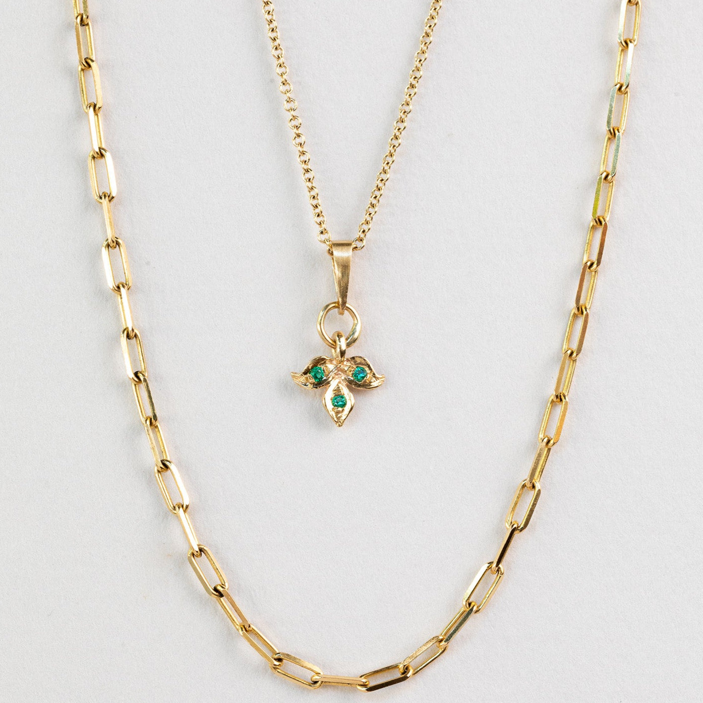 שרשרת זהב עדינה עם תליון עלה זהב משובץ בשלושה אבני אמרלד ירוקות. ושררת חוליות זהב מלבניות