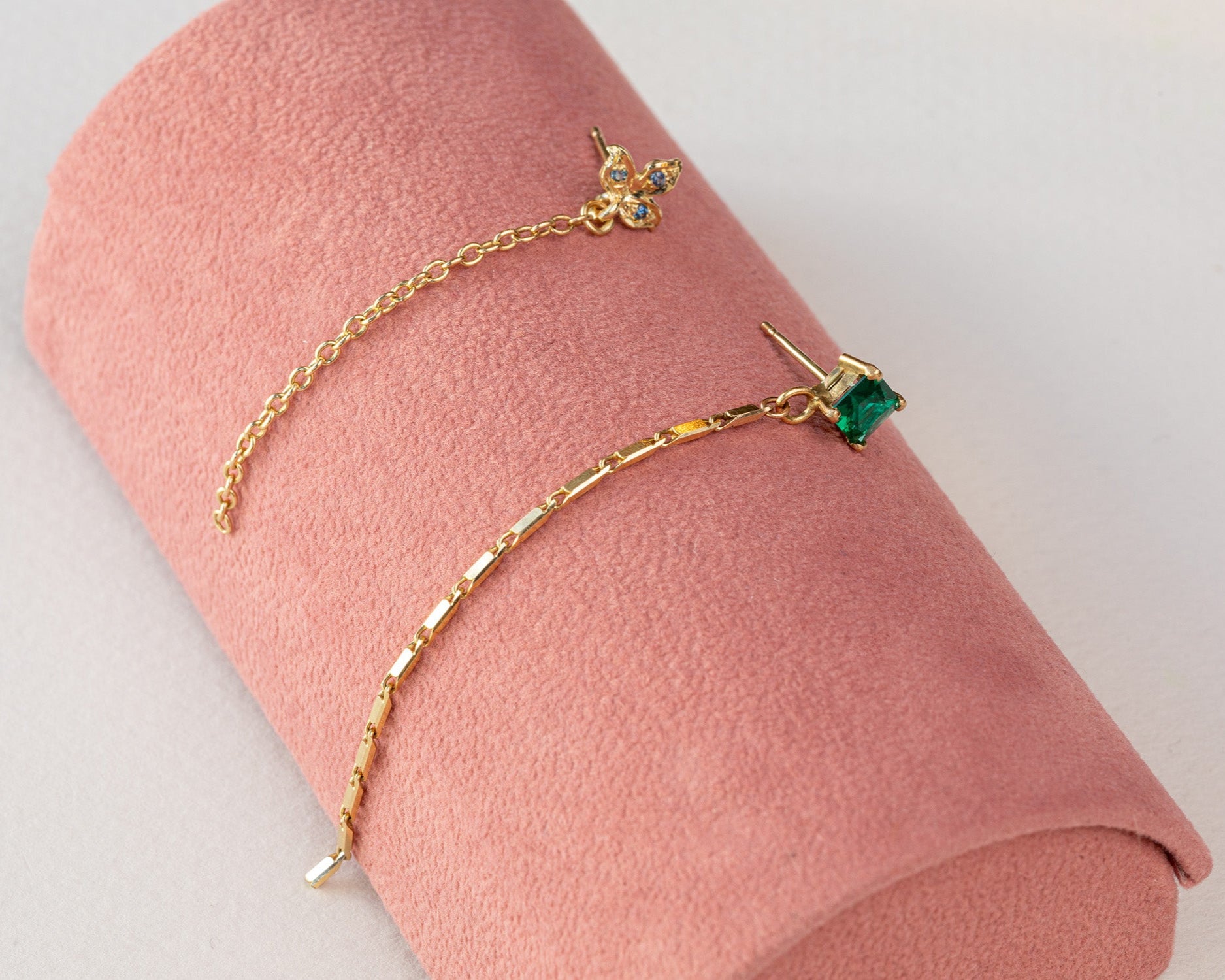 עגיל זהב מעוצב צמוד לאוזן עם אמרלד מעבדה מעויין שממנו יוצאת שרשרת זהב  ועגיל תלתן זהב משובץ בלו טופז עם שרשת חוליות זהב