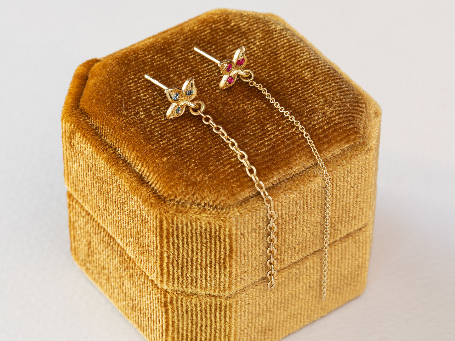 עגיל עלה תלתן מעוצב מזהב 14 קראט משובץ אבני בלו טופז עם שרשרת זהב משתלשלת ממנו.