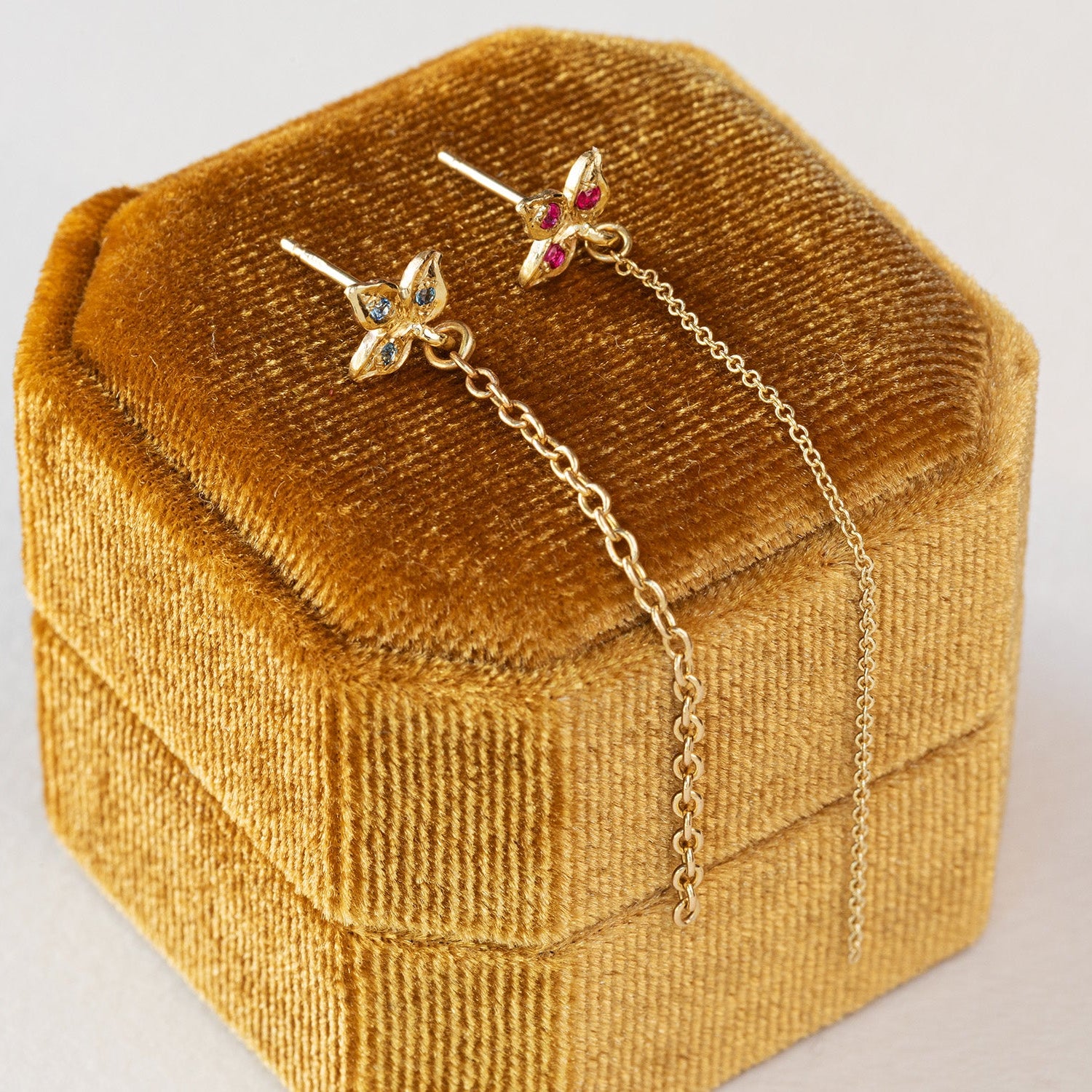 עגיל זהב  עלה תלתן צמוד אוזן  שממנו יוצאת שרשרת חוליות זהב. משוב אבני רובי 
