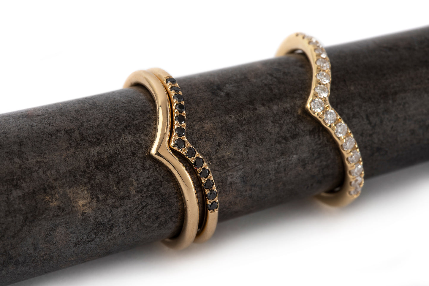 טבעת בצורת וי זהב משובצת יהלומים. טבעת זהב צהוב בעלת מבנה מעוגל שנגמרת בצורת וי משובצת15 יהלומים טבעיים. בתמונה מופיעה לצד טבעת וי עדינה יותר משובצת יהלומים שחורים וטבעת וי חלקה