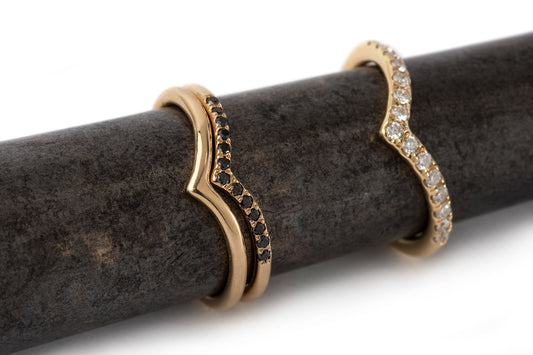 טבעת בצורת וי זהב משובצת יהלומים. טבעת זהב צהוב בעלת מבנה מעוגל שנגמרת בצורת וי משובצת15 יהלומים טבעיים. בתמונה מופיעה לצד טבעת וי עדינה יותר משובצת יהלומים שחורים וטבעת וי חלקה