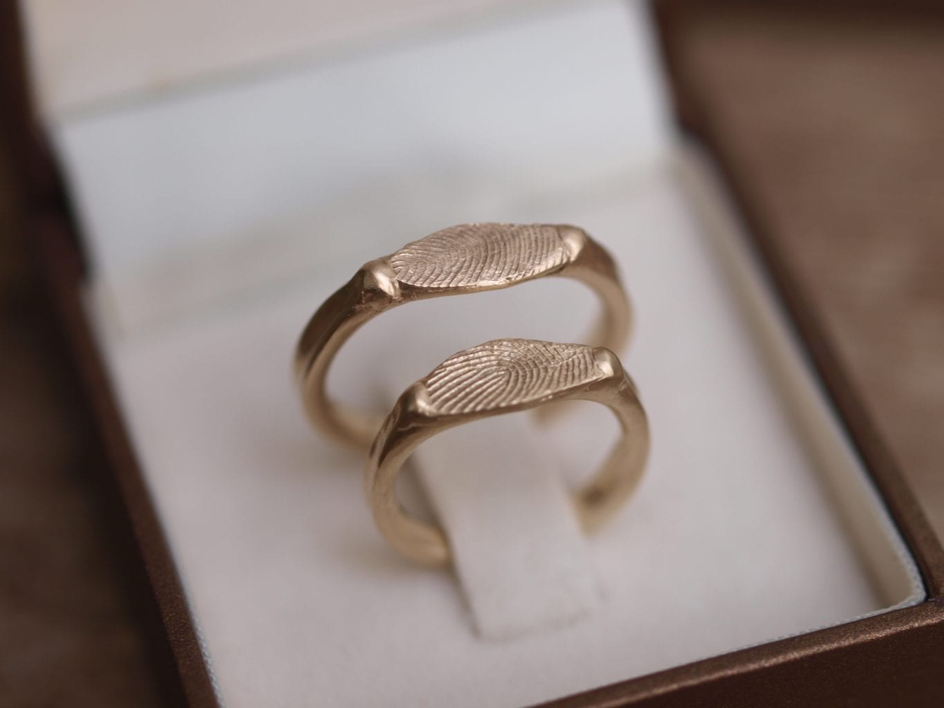 סט טבעות נישואים מעוצבות מזהב עם חותם עדין שעליו טביעת אצבע. על הטבעת שלו טביעת האצבע שלה ועל הטבעת שלה טביעת האצבע שלו.