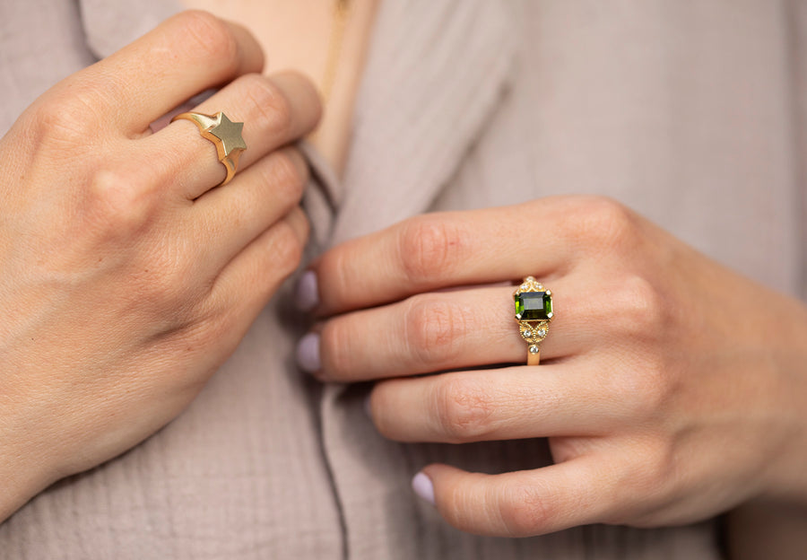 this photo features two beautiful rings.on the one is our star signet ring and on the other ourcocktail ring with green tourmalin gemstone and golden leafs set with diamonds.