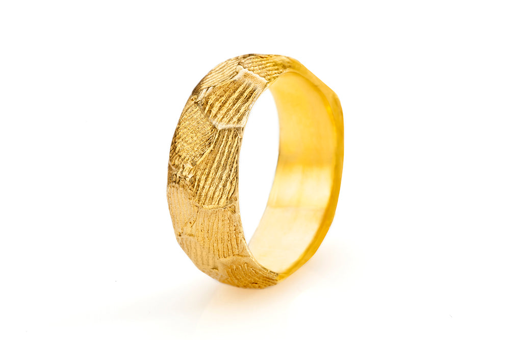 טבעת נישואין לאישה. טבעת זהב רחבה עם טקסטורה ייחודית שנוצרת על ידי טביעות האצבע האישיות מסביב לכל הטבעת