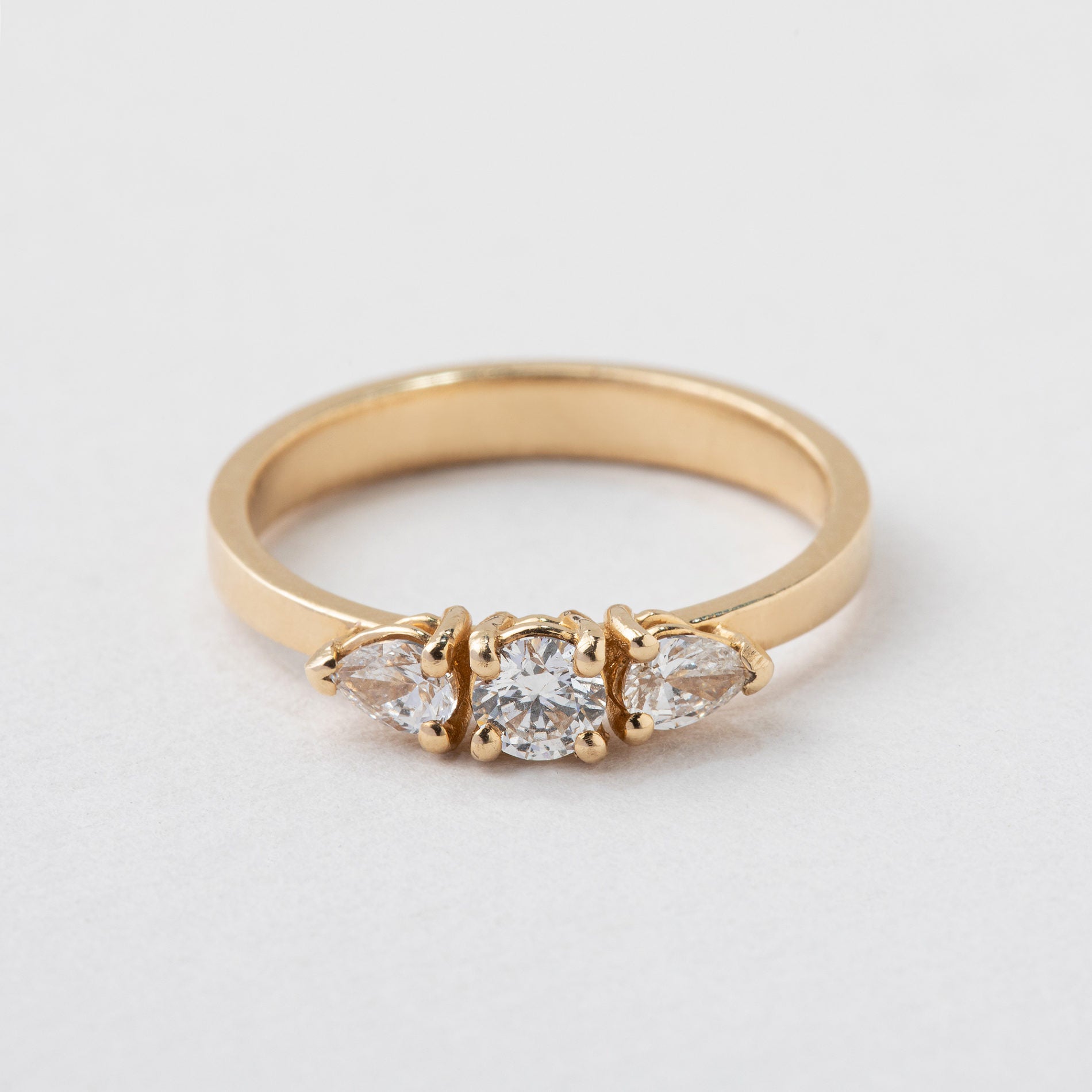 טבעת זהב בסגנון וינטאג׳ משובצת יהלומי מעבדה. במרכז יהלום מעבדה עגול ובשני הצדדים יהלומי מעבדה בחיתוך טיפה