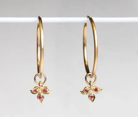 עגילי חישוק זהב גדולים עם תליון עלה תלתן מזהב  עשוי בעבודת יד ומשובץ בשלושה אבני רובי טבעיות.