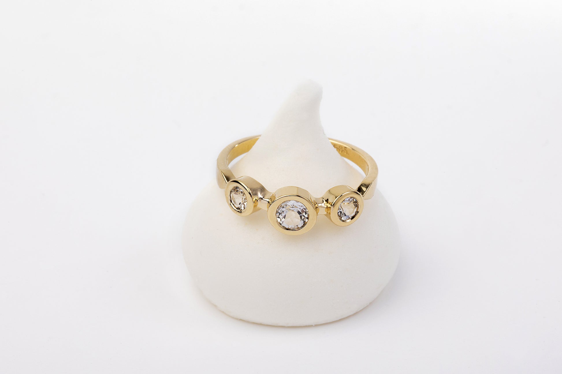 טבעת זהב אביב - טופז לבן זהב מאת Hydra Jewelry Studio, הכולל שלושה יהלומים עגולים משובצים בשוליים, שובה לב על גבי מעמד חרוט לבן פשוט.