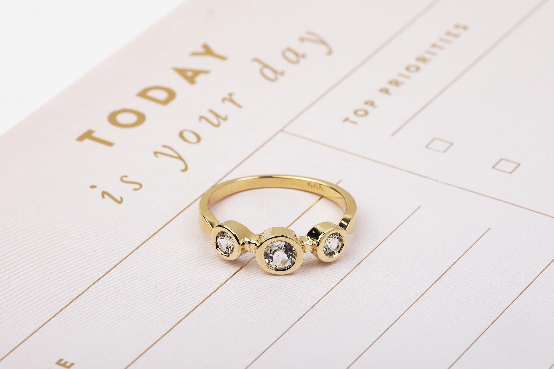 סטודיו טבעת זהב אביב - טופז לבן של Hydra Jewelry Studio, המעוטר בשלוש אבני חן עגולות, נשען על מתכנן המדגיש עיצוב אישי. המתכנן מציג את "היום הוא היום שלך" וכולל קטעים לסדרי עדיפויות עליונים.