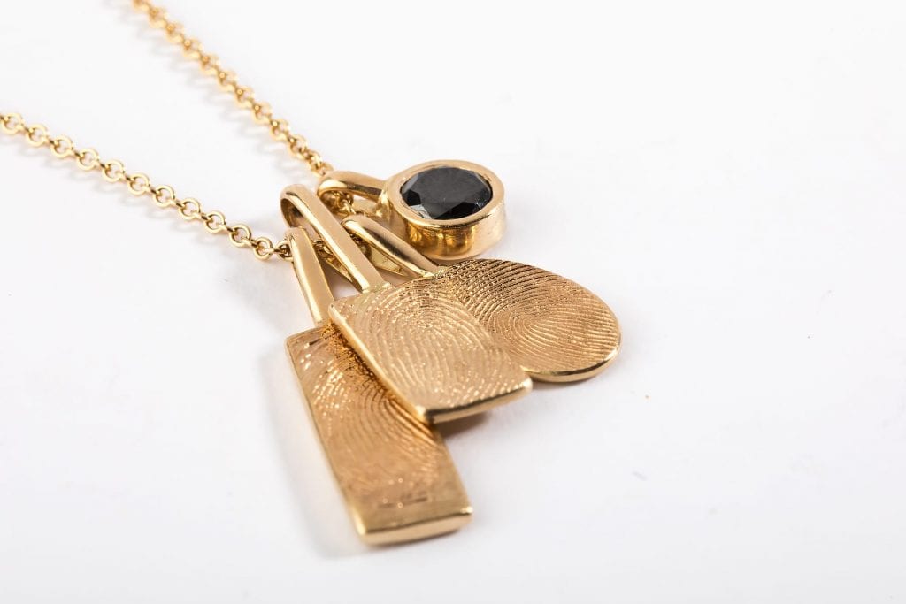 שרשרת טביעות אצבע מזהב. שילוב תליוני זהב עם טביעות אצבע אישיות ותליון אבן ספינל שחורה בכוס זהב