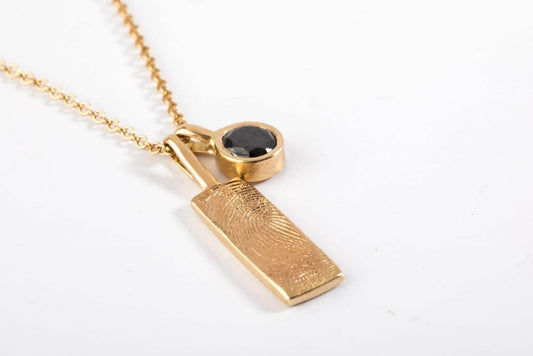 שרשרת זהב עם תליון מלבן ארוך שעליו טביעת אצבע אישית יצוקה בזהב ותליון זהב עגול בצורת כוס קלאסית משובץ אבן שחורה