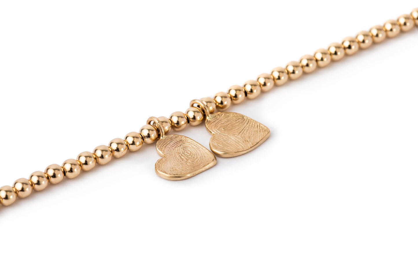 צמיד חרוזי זהב ותליוני לבבות זהב עם טביעות אצבע אישיות. צמיד לאישה בעבודת יד עשוי זהב 14 קראט.
על תליוני הלב טביעת אצבע אישית שנעשית בשעווה ויצוקה בזהב.