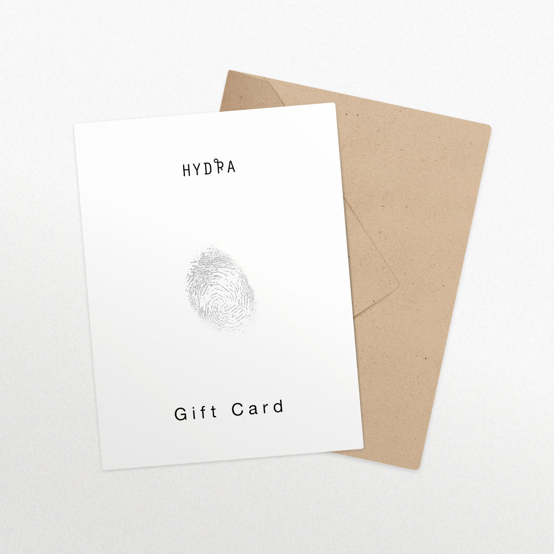 גיפט קארד לבן בעיצוב טביעת אצבע מסטודיו Hydra Jewelry, מונח על מעטפה חומה על משטח לבן.