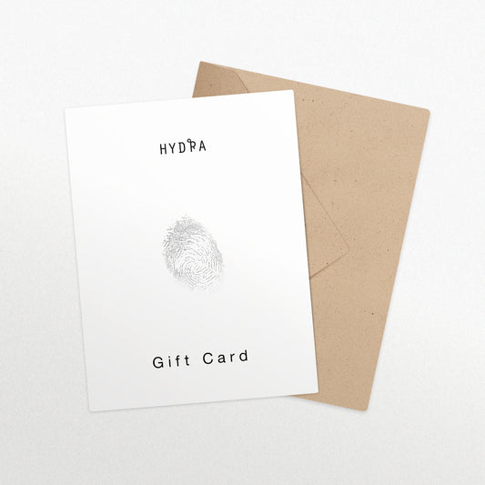 גיפט קארד לבן בעיצוב טביעת אצבע מסטודיו Hydra Jewelry, מונח על מעטפה חומה על משטח לבן.